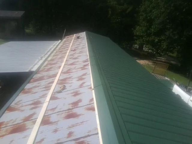 Old rusted panels beside newly installed green metal roofing — Wind Damage Roof Repair by Roofing Brothers in Acworth
