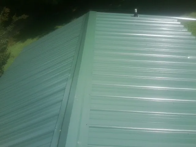 New green metal panels meeting at the ridge of a roof — Flat Roof Repair work by our crew in Acworth