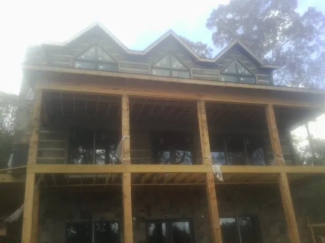 Dormers and porch framing on a large log home under construction — Roof Coating work by our crew in Acworth