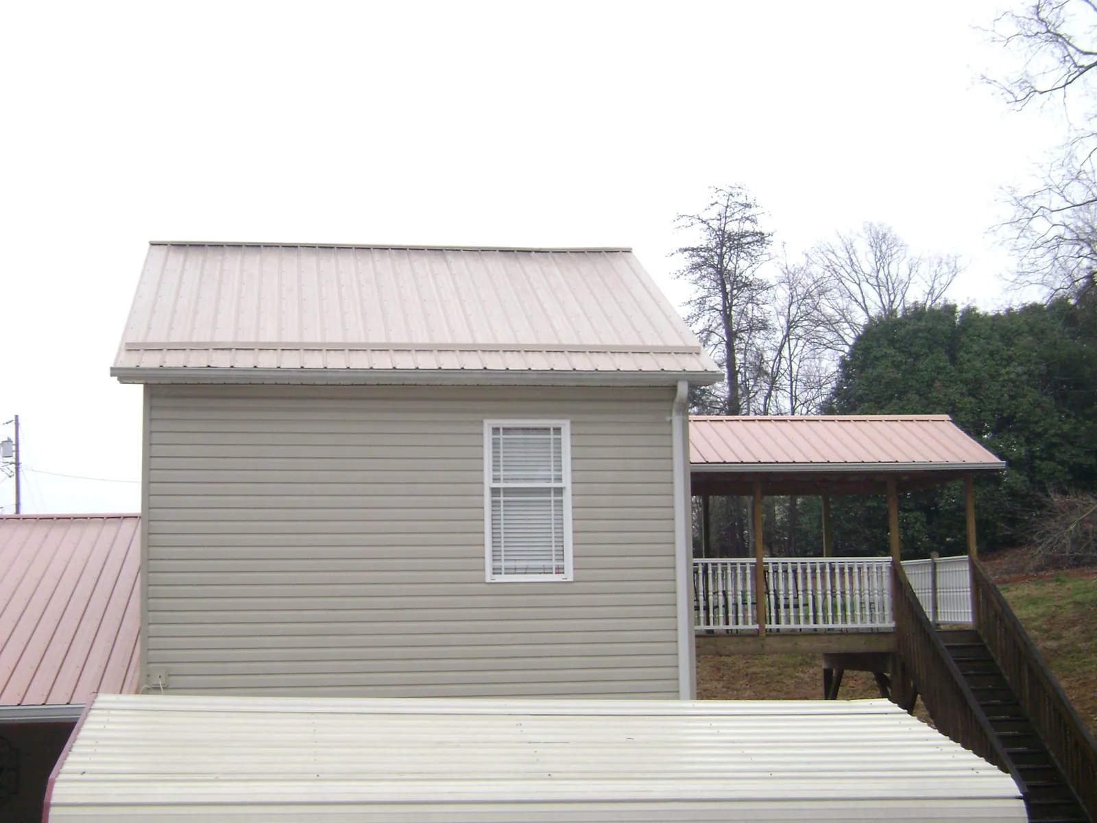 Tan metal roofs on a two story addition and attached porch, from a Roof Replacement job in Acworth