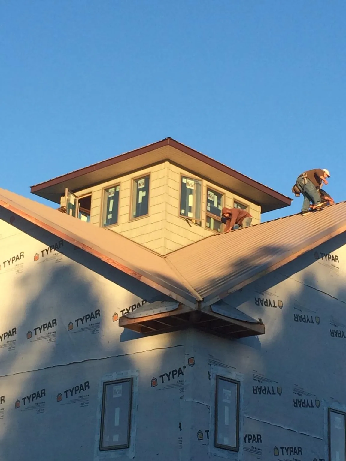 Roofers working around a rooftop cupola on a new metal roof at sunset — Roof Waterproofing in Acworth by Roofing Brothers
